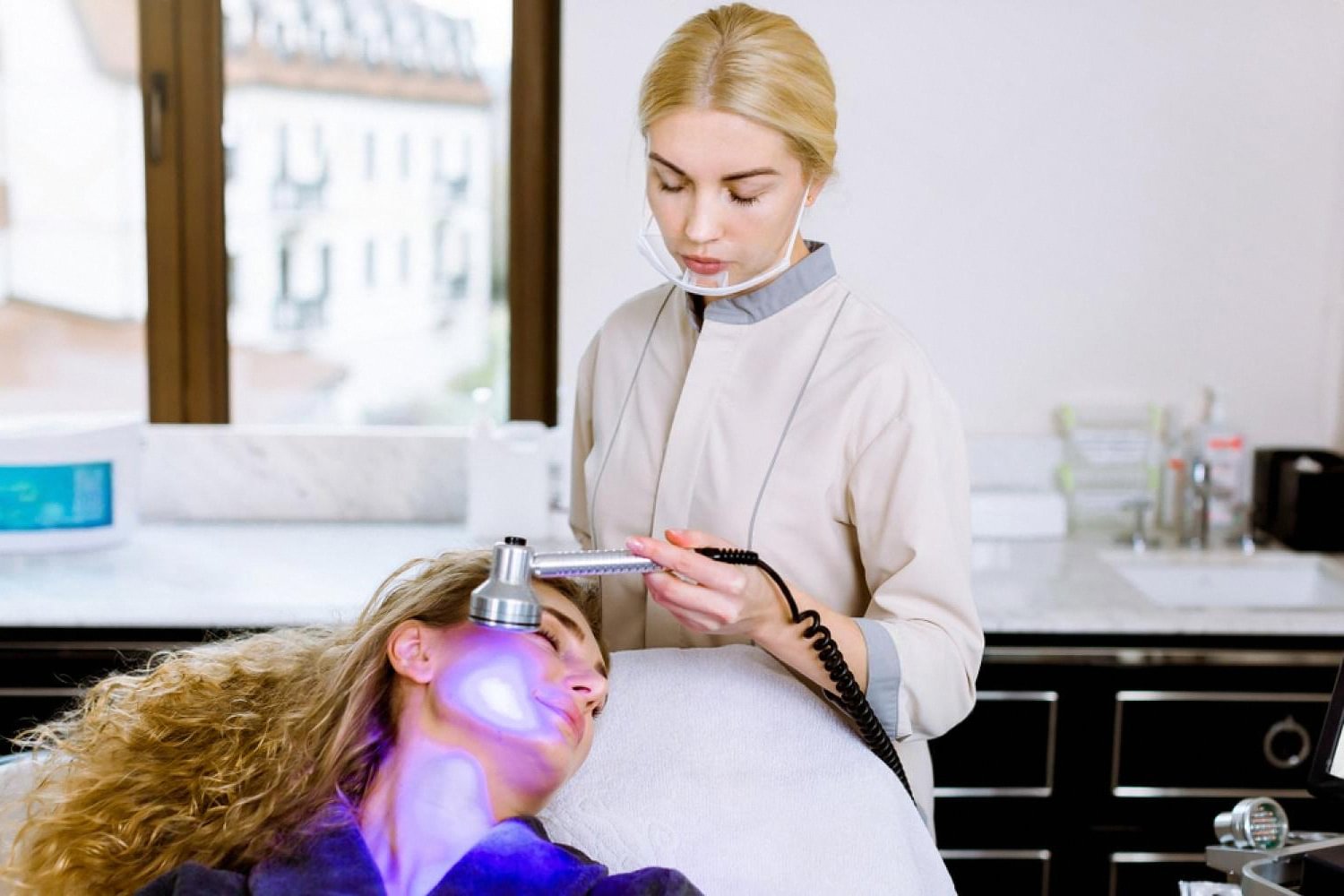 Aesthetician performing a light-based skin treatment on a patient at an aesthetic clinic