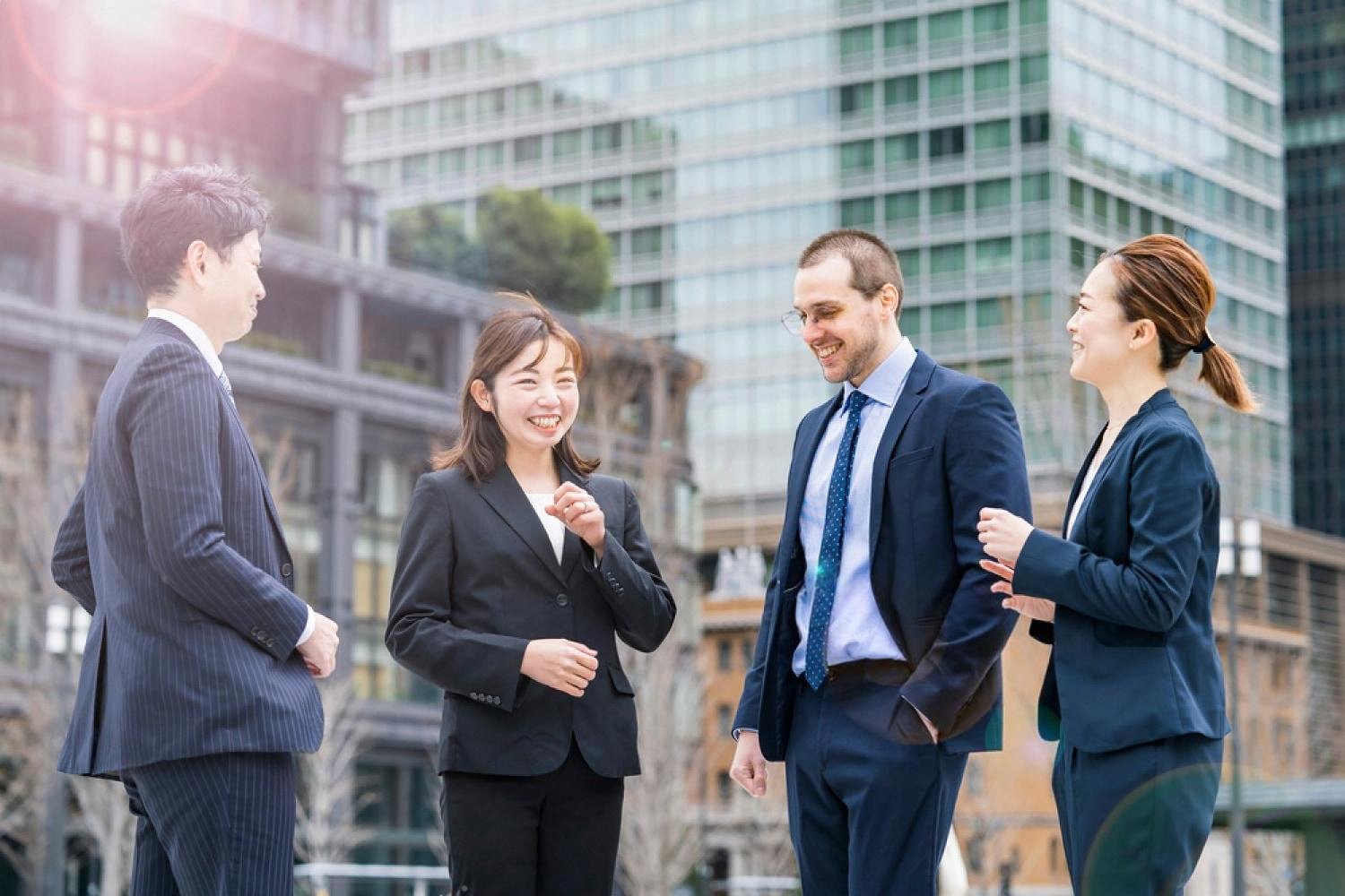 Cross-cultural business team of four professionals talking outside a Dubai office building
